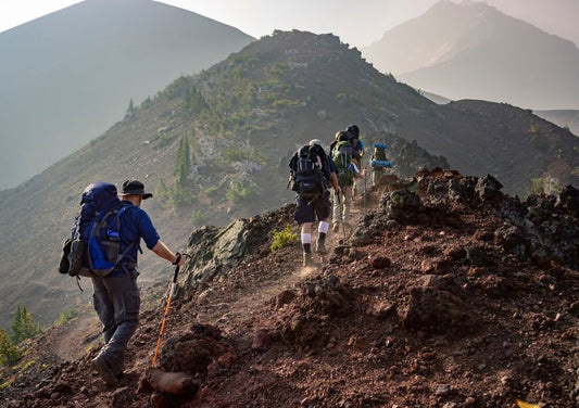 three people hiking up a mountain